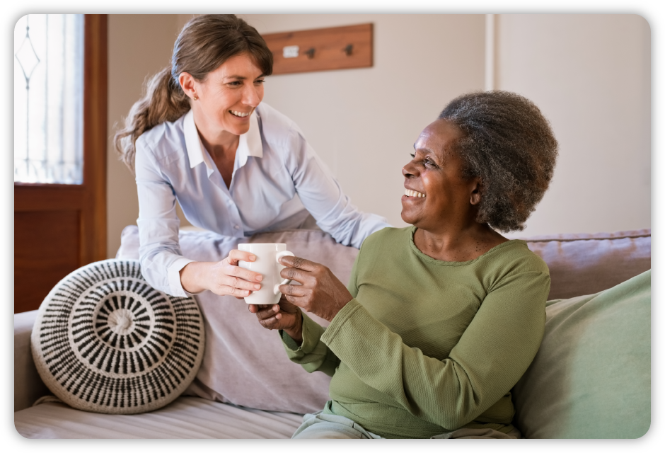 caregiver handing happy lady a mug